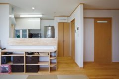 カウンターに収納棚を造作したキッチンは、リビング側からも出入りできる脱衣所と隣接。家事がしやすい動線である