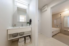 シンプルで白色を基調とした洗面室と脱衣室は扉があり、家族のプライバシーを確保