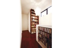 2階の階段フロアに棚を造作し、本やCDを収めて趣味の空間に