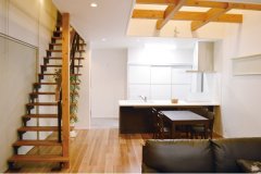 白の内壁に濃色の家具を合わせたモダンテイストのリビング。キッチン上部の豪快な吹き抜けが開放的な空間を演出