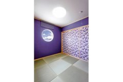 深紫の壁紙が印象的な1階客間は、和モダンな仕上がり。夜中に床についた際に星空が見えるようこだわった丸窓は、デザイン性においても重要なアクセントになっている