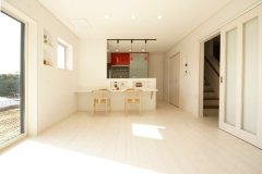 白を基調とした空間に、鮮やかな赤いキッチンが映えるLDK。  食卓をダイニングカウンターにしてなるべくスペースを抑え、その分リビングを広くとっている。 