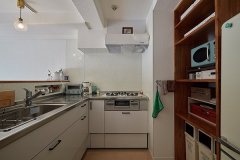 料理好きな施主にぴったりのL字型キッチンは下がり壁を取って明るく。ゴミ箱や家電が収まる棚は、大きさに合わせて造作した。