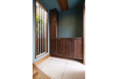 青い壁が個性的な玄関。造作の靴箱やアンティーク調のタイル床が品格を感じさせる
