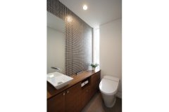 効果的に採光できるスリット窓を採用することで、プライバシーに配慮したトイレ。造作の収納や壁紙・タイルでラグジュアリー感を演出。