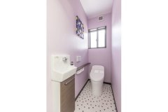 奥さまがセレクトした、壁面のパープルのカラークロスと、足元のドット柄のクロスが可愛らしくまとまったトイレ。