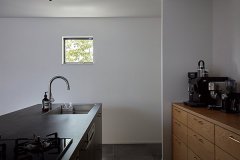 キッチン台のグレーとオークの木肌、小窓に映るアオダモの緑が空間のアクセントに。