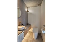 間接照明が足元を照らすトイレ。モールテックスの壁に、水栓や照明といった真ちゅうのアイテムがよく合います。